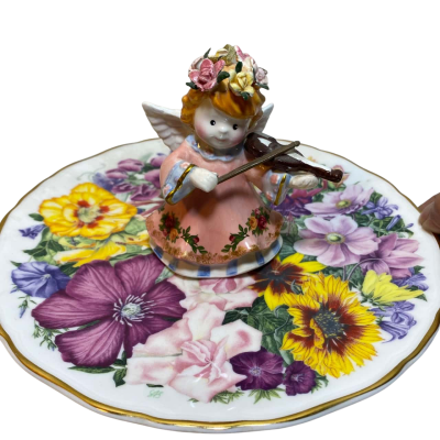 an angel playing a violin, placed on a floral-patterned plate.