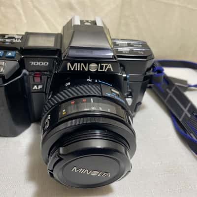  a Minolta Maxxum 7000 AF 35mm film SLR camera equipped with an AF zoom lens, notable for being the first-ever camera with an integrated autofocus system and motorized film advance