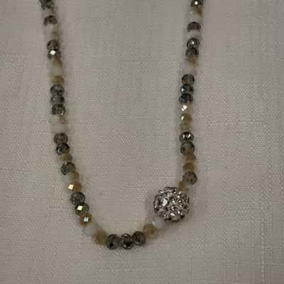 Long beaded necklace featuring small white in translucent grey faceted beads with a small parveetry crystal ball pendant at the end