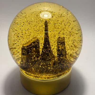 Paris Themed 12cm High Plastic Snow Globe featuring golden monuments and glitter