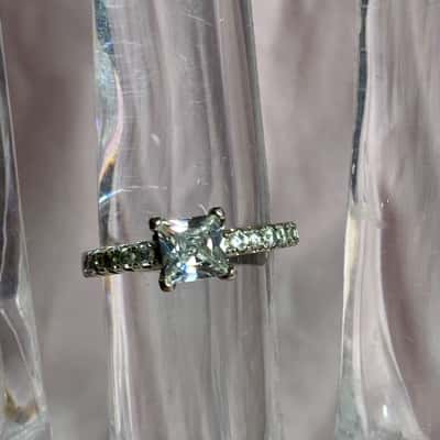  925 SILVER RING WITH ONE LARGER AND SOME SMALLER CLEAR STONES ALONG BAND US 9.5