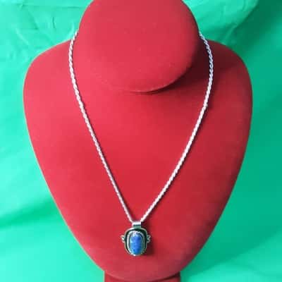 Blue gemstone pendant necklace set in Silvertone featuring an oval shape Stones surrounded by rope-like border