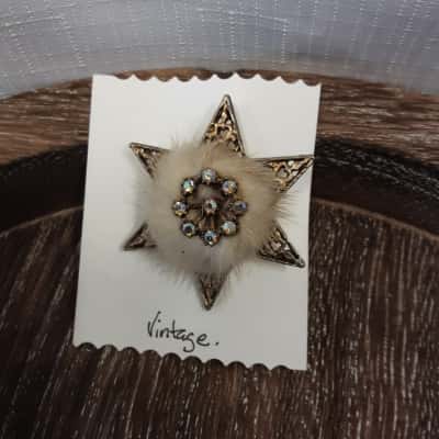 Vintage brooch featuring a Central floral cluster of iridescent Stones surrounded by soft white fur all set within eight Gold Tone metal star