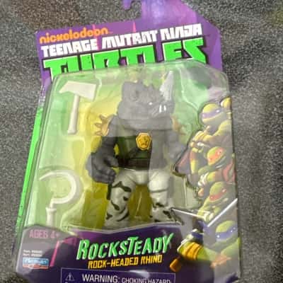 Playmates Toys Nickelodeon Teenage Mutant Ninja Turtles Rocksteady action figure. It includes accessories such as a pickaxe and a sickle.(B8)