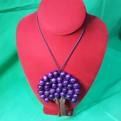 Handcrafted tree of life necklace featuring wood trunk and purple beaded foliage 