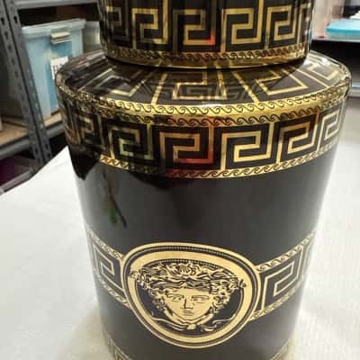 Medusa-style ceramic canister, a decorative storage jar featuring a prominent Medusa head motif and classic Greek key (meander) patterns. Glossy black ceramic base with gold-tone detailing, including the iconic Medusa emblem (B9)