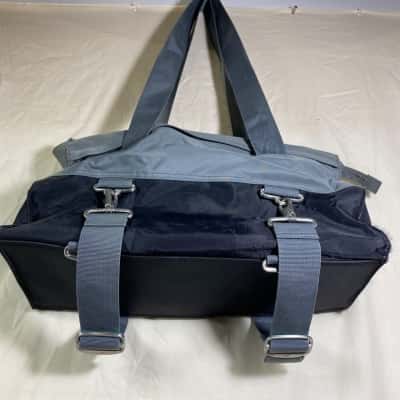 a grey and black Nike gym bag or duffel featuring distinctive metal hardware clips and a small yellow embroidered Swoosh logo