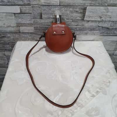 vintage round metal hip flask housed in brown leather case