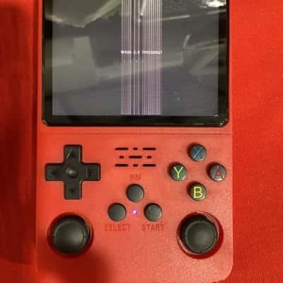 R36S+ handheld gaming console with charging cord.