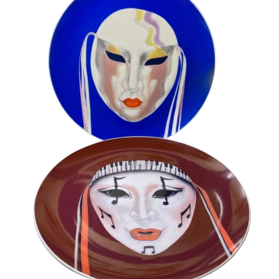 vintage decorative porcelain plate featuring a theatrical or masquerade face mask against a deep blue background