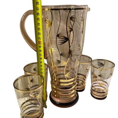 a vintage pink or peach-tinted glass lemonade pitcher and tumbler set decorated with gold gilded bands and black weed or floral motifs