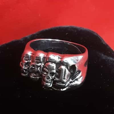 Men's silver tone ring featuring a skull face and fist design