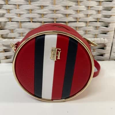 Womens Statement Crossover Bag, featuring a round, structured design with a distinctive red, white, and blue vertical stripe accent and a gold-tone monogram logo on the front