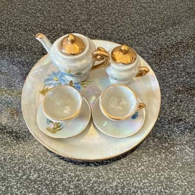 Collectible miniature porcelain tea set with a blue floral pattern and gold trim. It includes a teapot, a smaller creamer or sugar bowl, two teacups, two saucers, and a serving tray. (B12)
