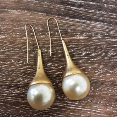 Gold Tone long drop style earrings featuring large faux Pearl detail