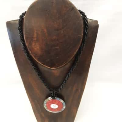 Handcrafted necklace featuring a circular pendant inlay with red shell and shimmering abalone on a Twisted Black beaded Strand necklace