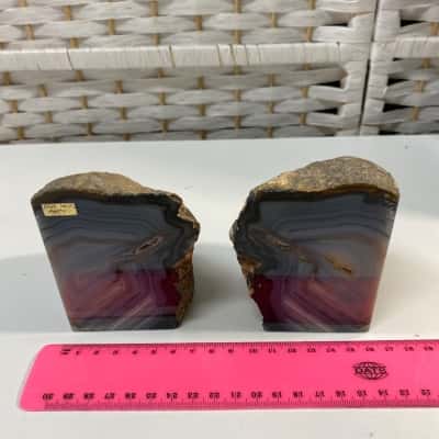 pair of polished banded agate bookends featuring concentric grey and brownish-grey mineral layers with a rough, natural outer rind